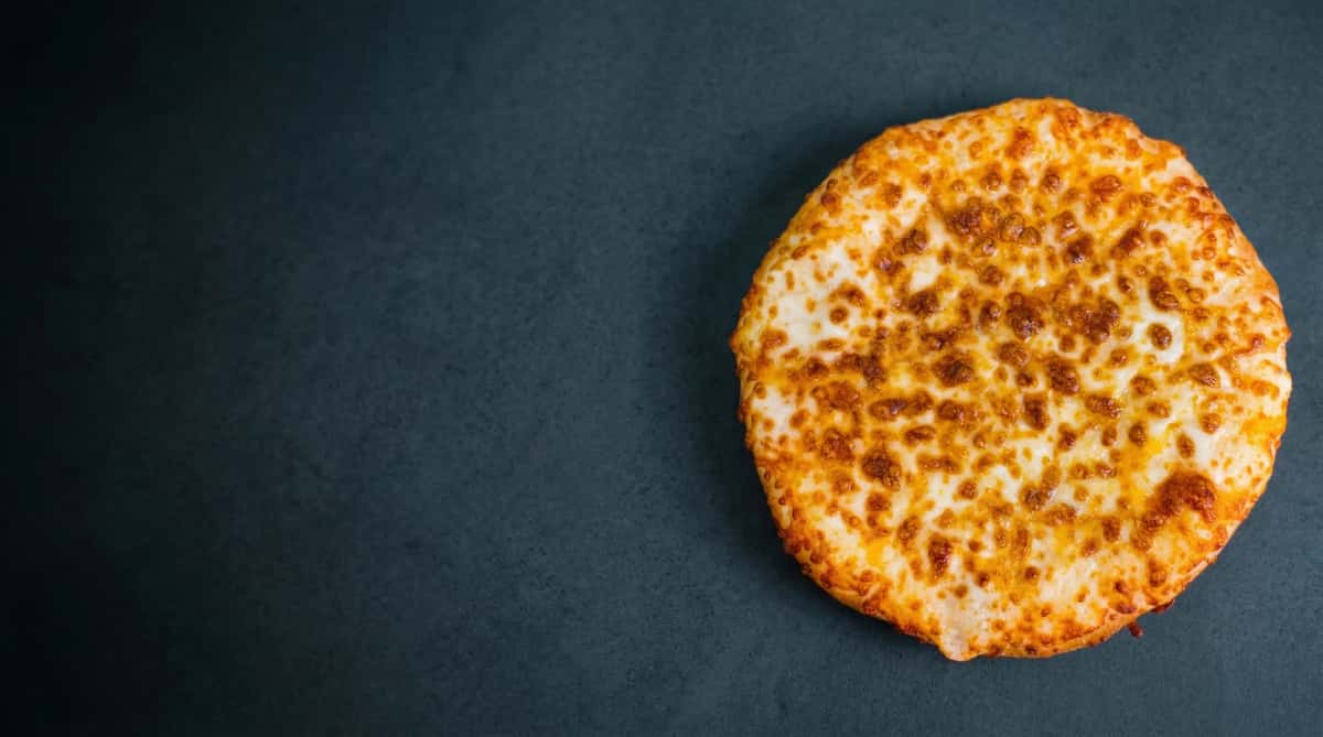 Round garlic cheese bread with melted, browned cheese on a red background.