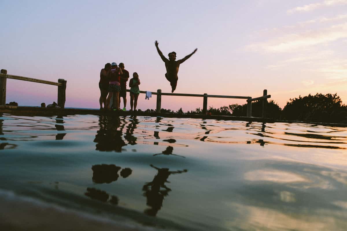 Group on a lake dock jumping off into the water