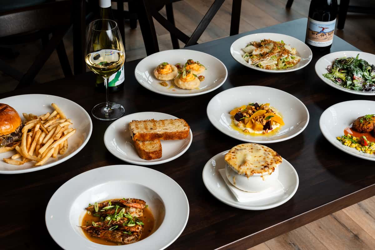 Southern-inspired family-style dining spread with burgers, seafood, and wine at Oxford Place