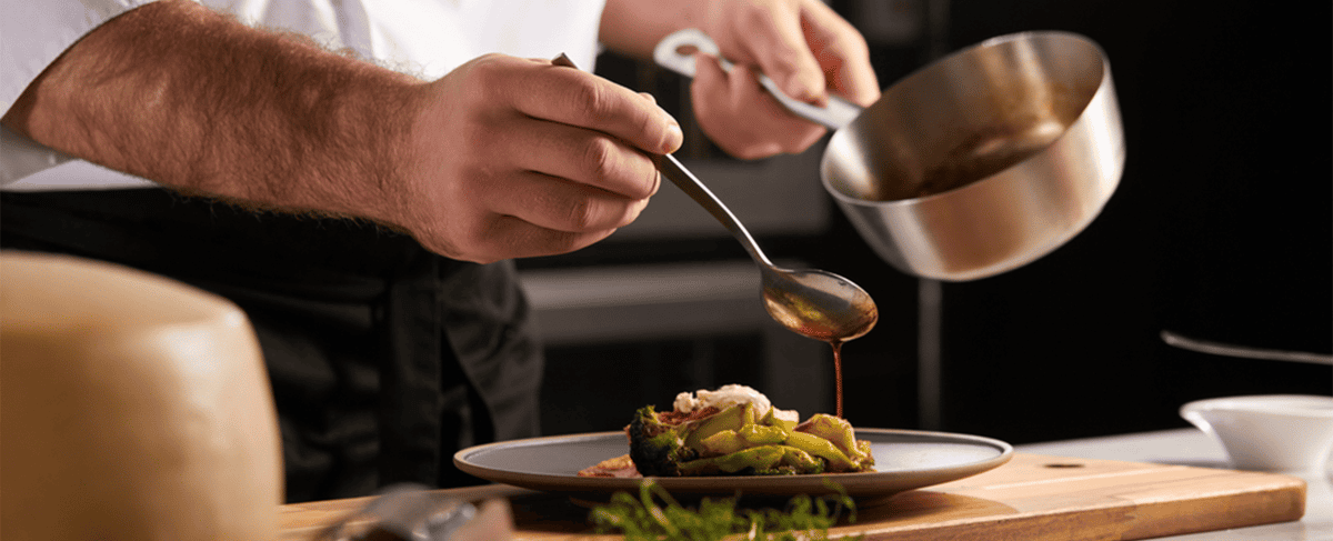 Chef drizzling sauce on a dish