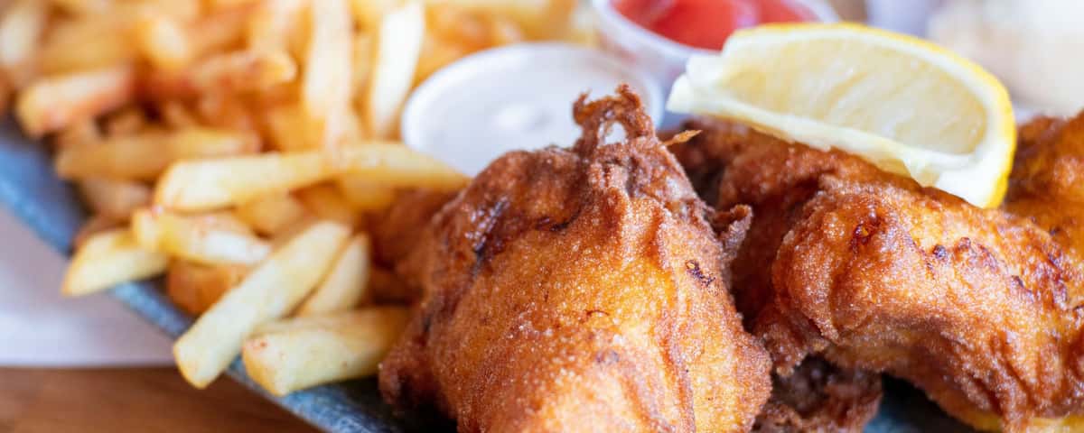Crispy battered fish and golden chips served with lemon wedges and dipping sauces