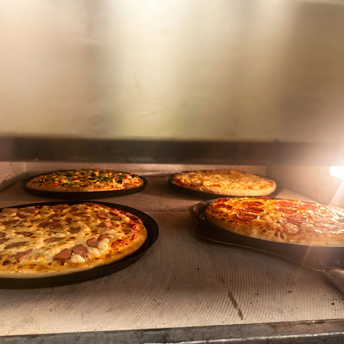 Freshly baked pizzas with assorted toppings inside a hot restaurant pizza oven