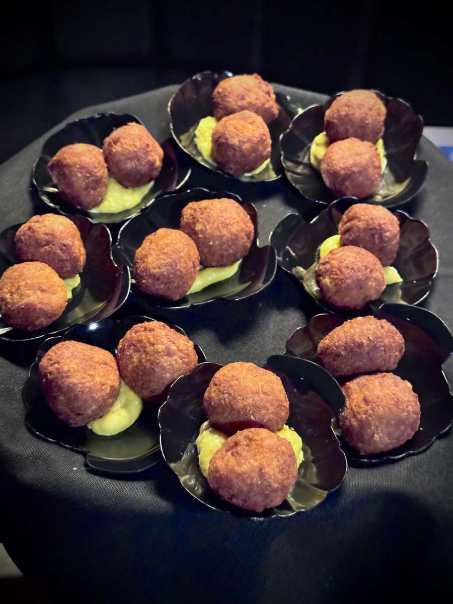 Golden-brown fried appetizers served over a yellow cream sauce in small black shell-shaped bowls at The Grove Cucina & Wine.