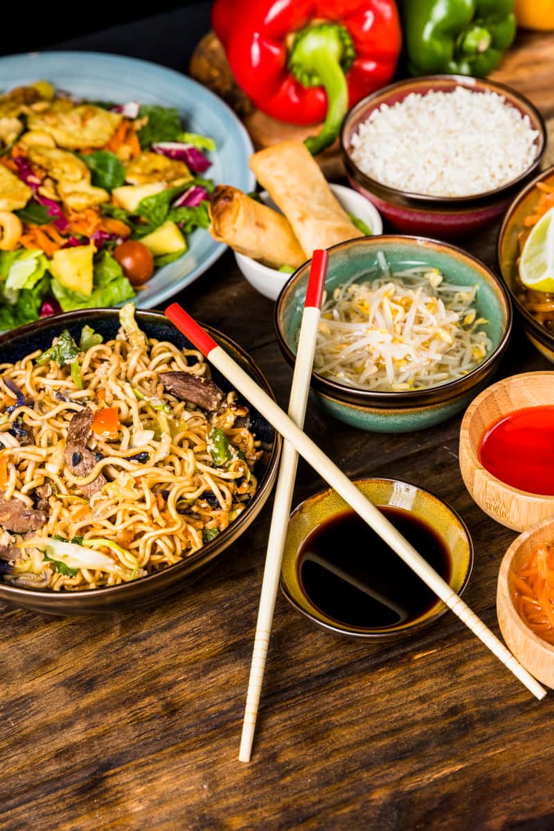 Asian noodles spread on a table with sauces and rice