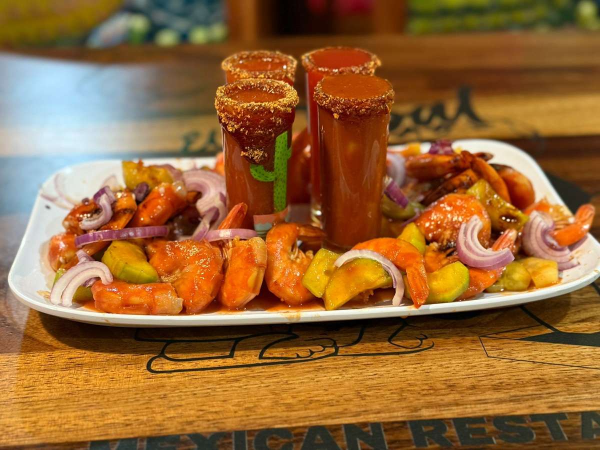 Spicy shrimp cocktail served with sliced cucumber, red onion, and four rimmed shots of clamato-style michelada mix.