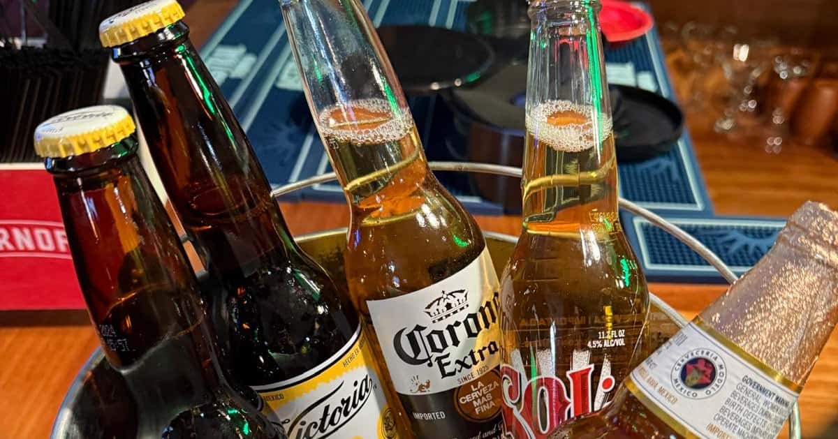 Bucket of assorted Mexican beers including Victoria, Corona Extra, and Sol on a bar counter.