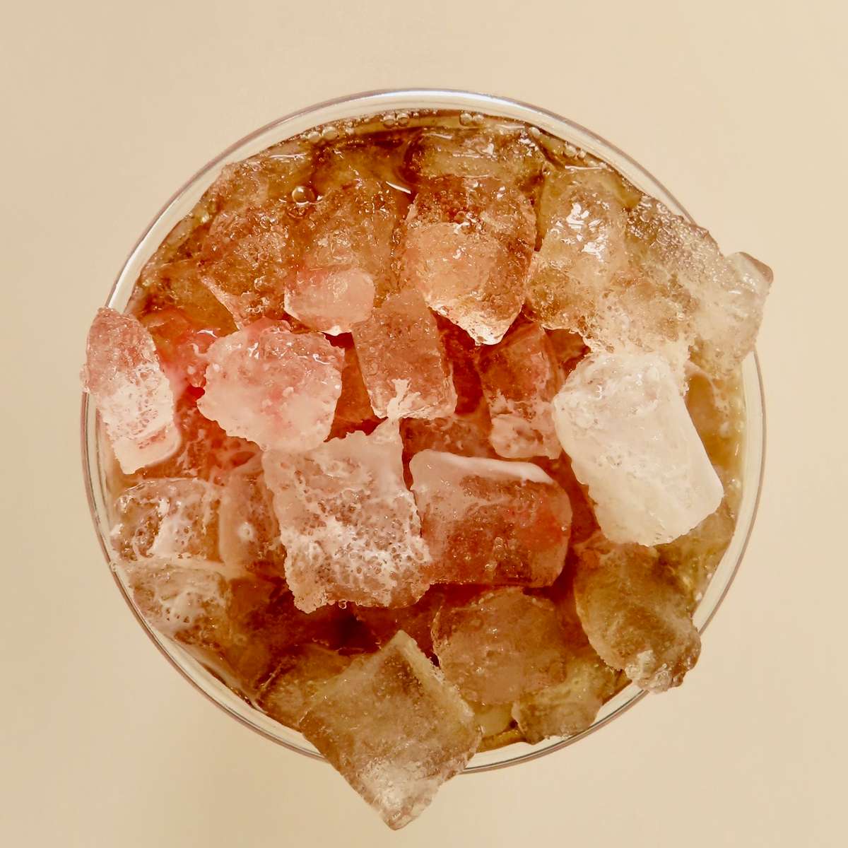 Iced cola soft drink in a clear cup filled with frosty ice cubes, featuring bubbly carbonation and chilled soda—refreshing fountain drink perfect for fast food restaurants, casual dining, or summer beverage menus.
