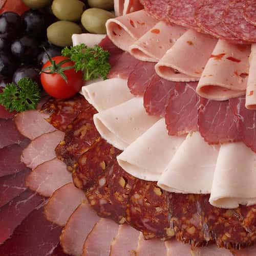 Assorted Italian cold cuts laid out with olives and tomatoes