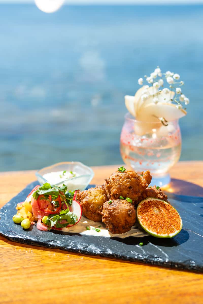 Crispy fried seafood bites with fresh lime, dipping sauce, and waterfront cocktail service at an upscale restaurant