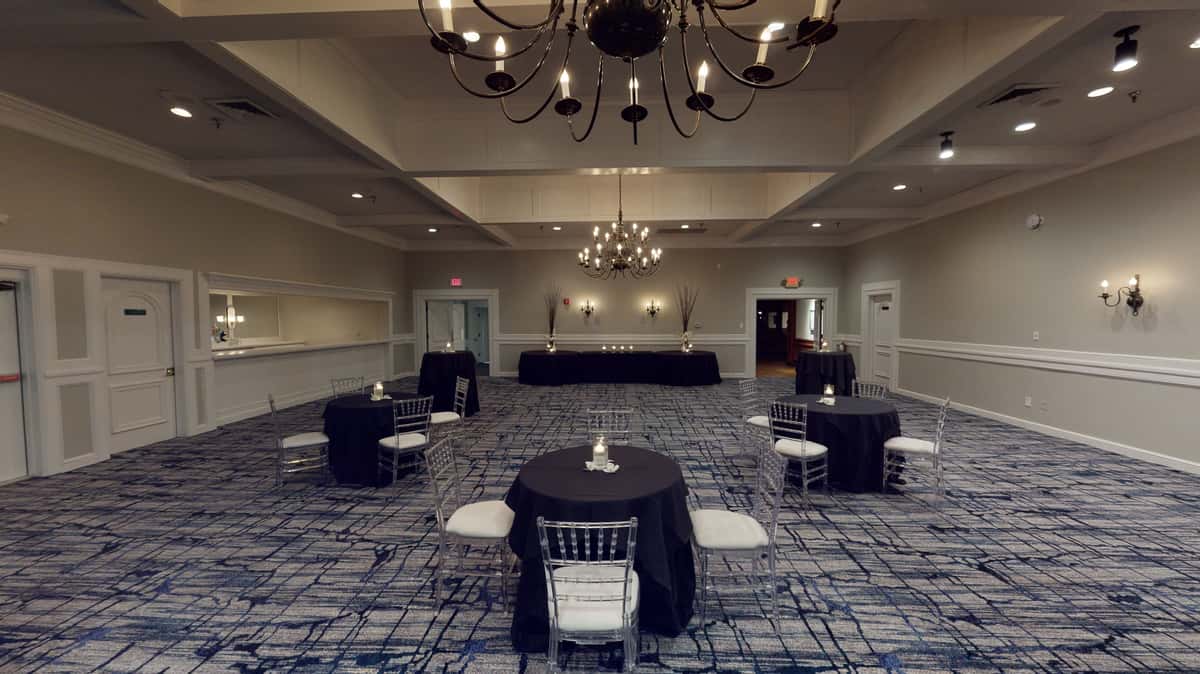 Spacious ballroom event venue with black cocktail tables, chandeliers, and elegant neutral decor for private receptions and corporate events