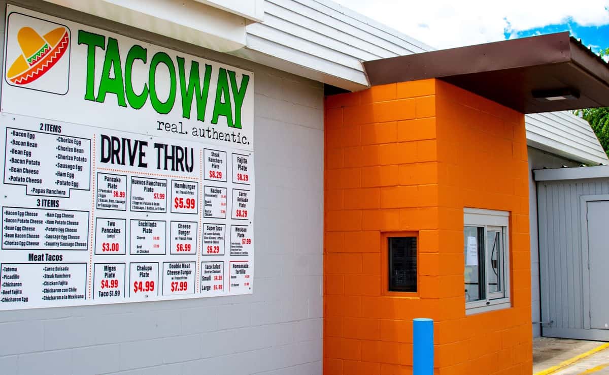 Drive thru window of Taco Way with a large menu on the wall