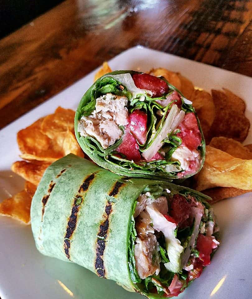 chicken wrap with lettuce, tomatoes with a side of chips