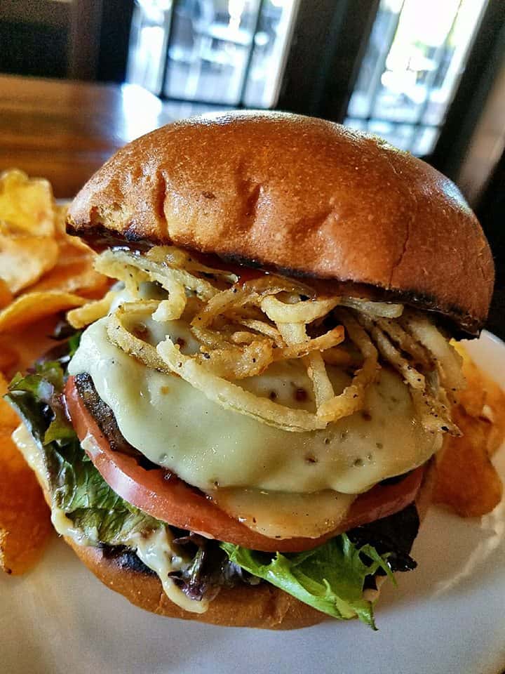 cheeseburger with lettuce, tomato topped woth crispy onions and a side of chips