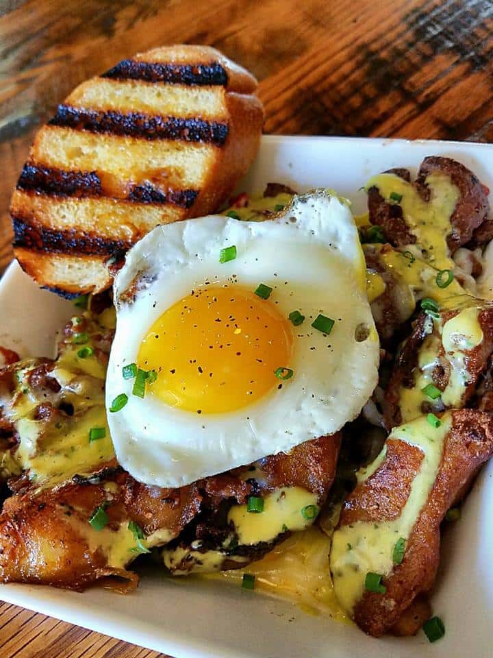 fried egg over loaded potatoes and a side of garlic bread