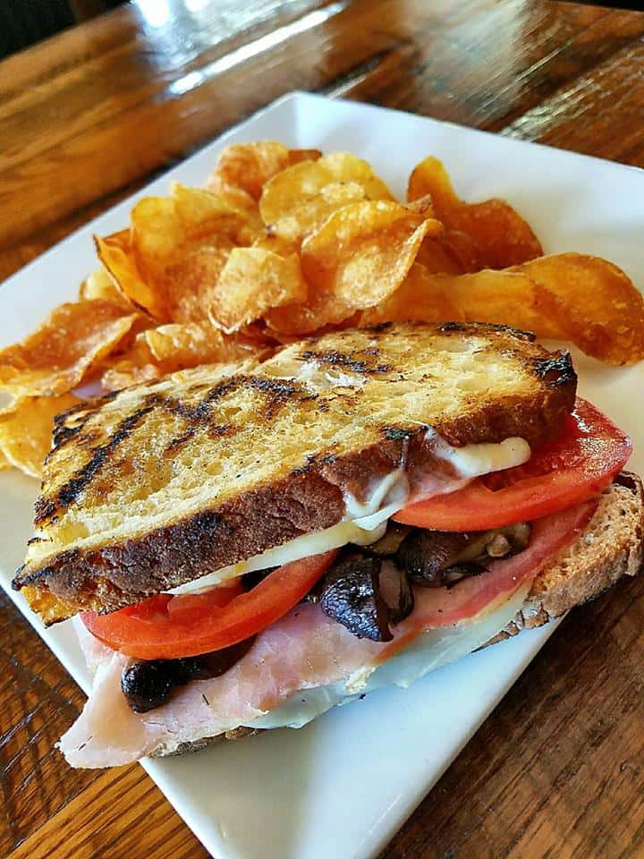 ham sandiwch with cheese, mushrooms and tomatoes with a side of chips