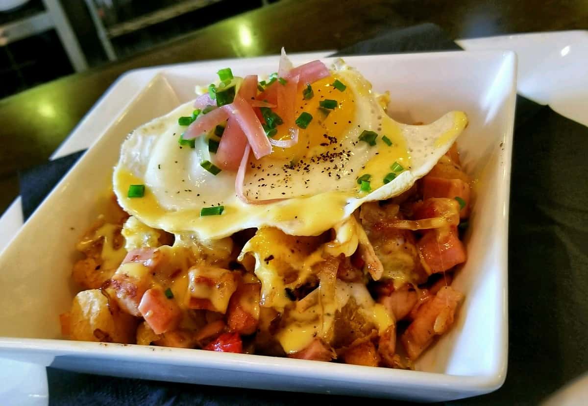 loaded hashbrowns topped with a fried egg and herbs