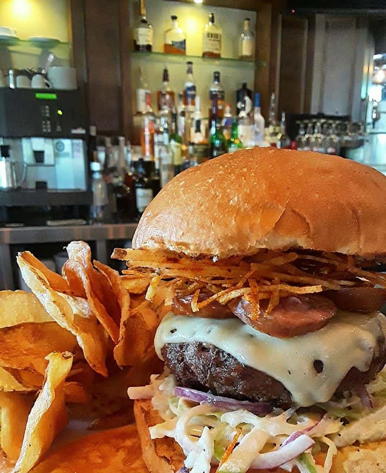 cheeseburger topped with hashbrowns with a side of chips