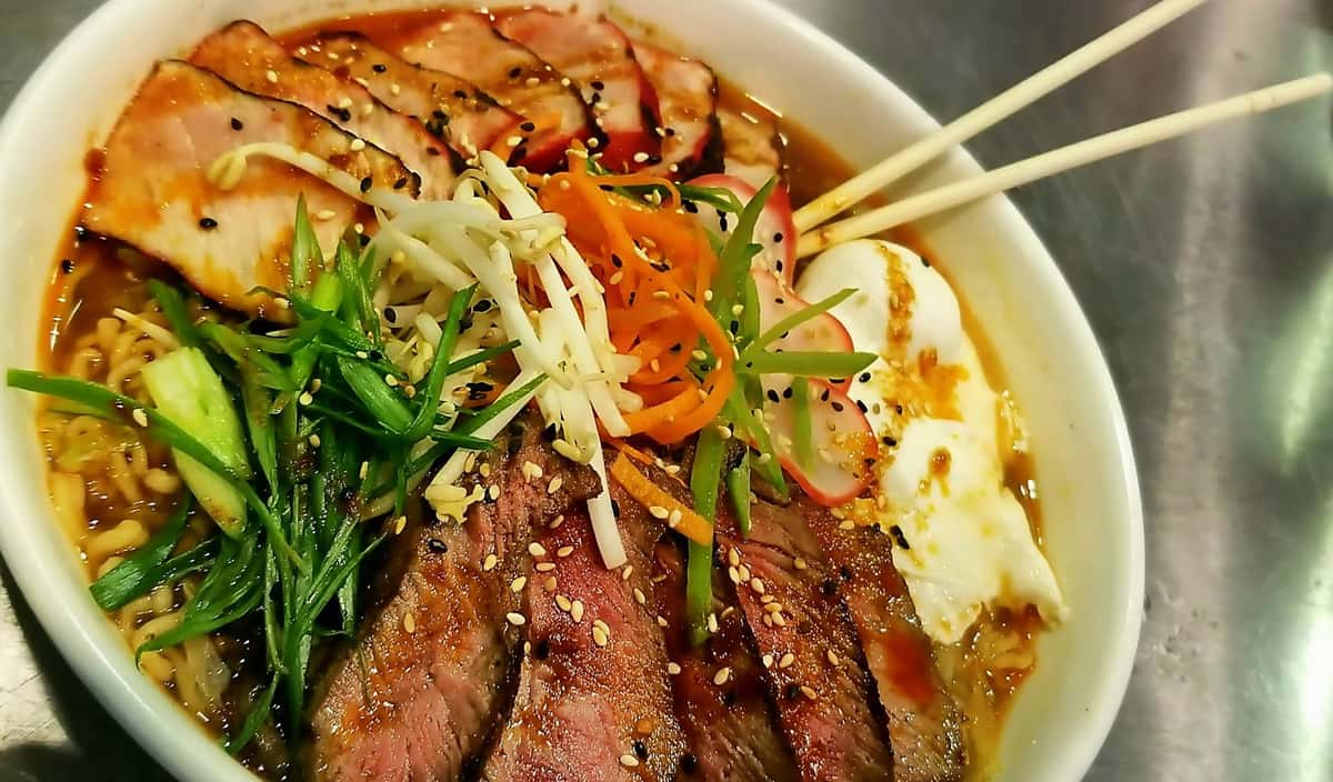 sliced beed with a fried egg in broth with vegetables
