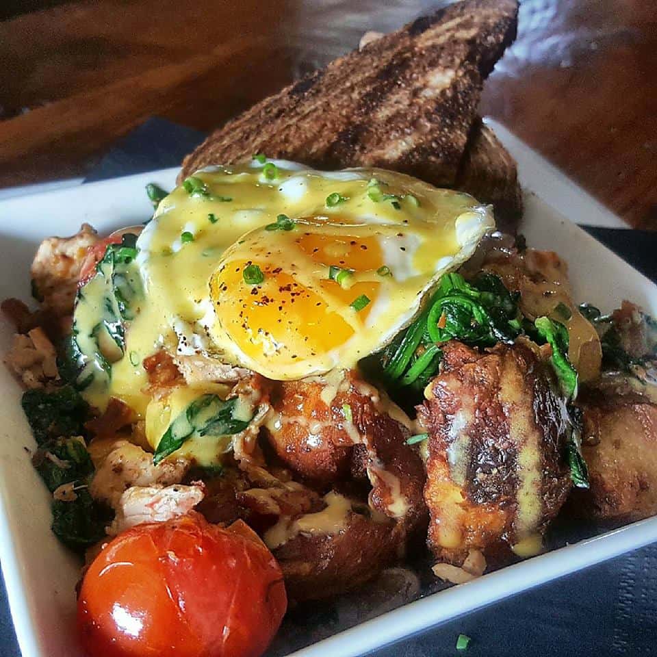 cooked seasoned chicken with vegetables topped with a fried egg