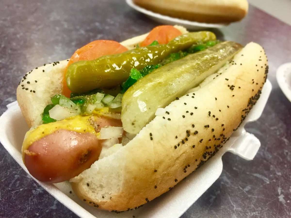 Classic Chicago-style hot dog topped with mustard, relish, onion, tomato, pickle spear, and sport peppers in a poppy seed bun.