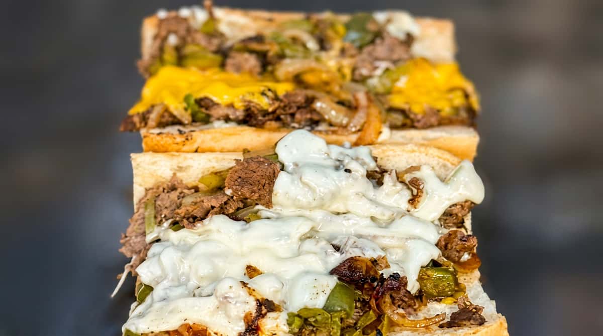 Philly cheesesteak sandwich with steak, melted provolone, green peppers, and onions.