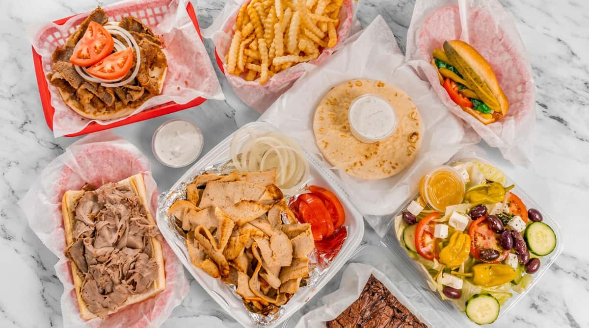 Assortment of takeout foods including gyros, fries, subs, and a Greek salad.
