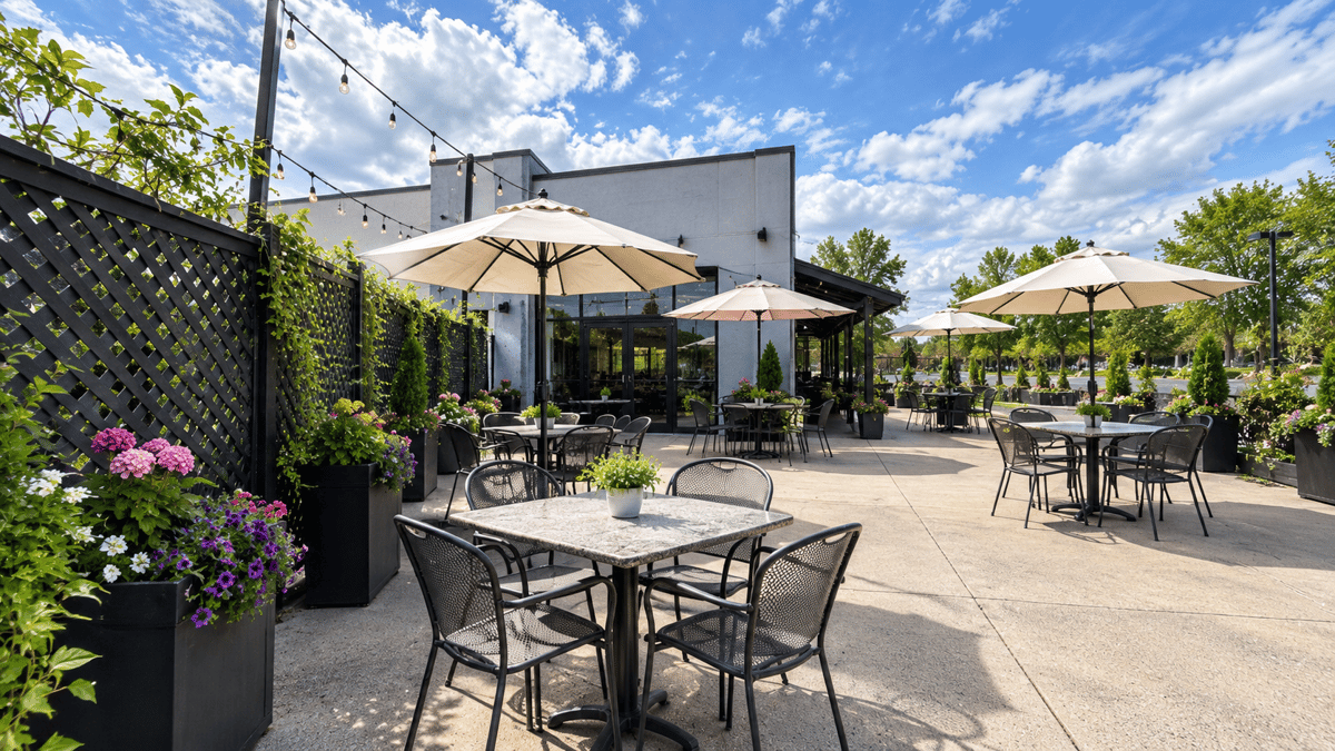 Bright Avenue Bistro patio with outdoor dining tables, umbrellas, flowers, and a blue sky.