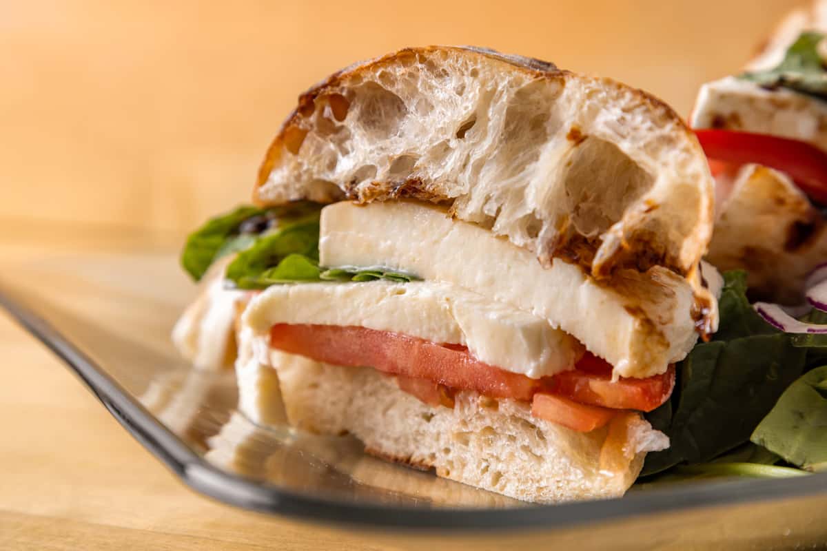 Close-up of fresh mozzarella sandwich with tomato, basil, and crusty bread