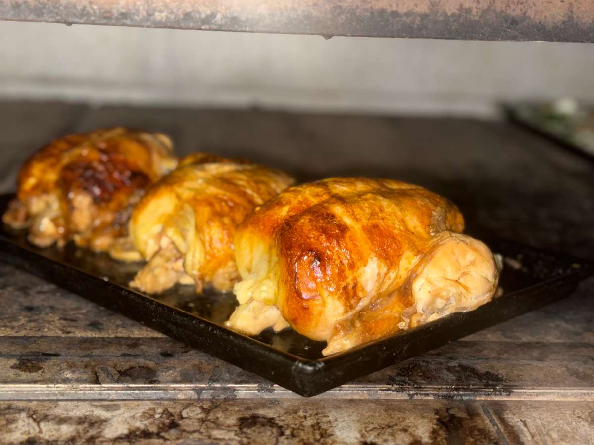 Three whole rotisserie-style chickens roasting in a commercial oven, featuring crispy golden-brown skin and juicy, tender meat—ideal for restaurant-style roasted chicken or catering service.