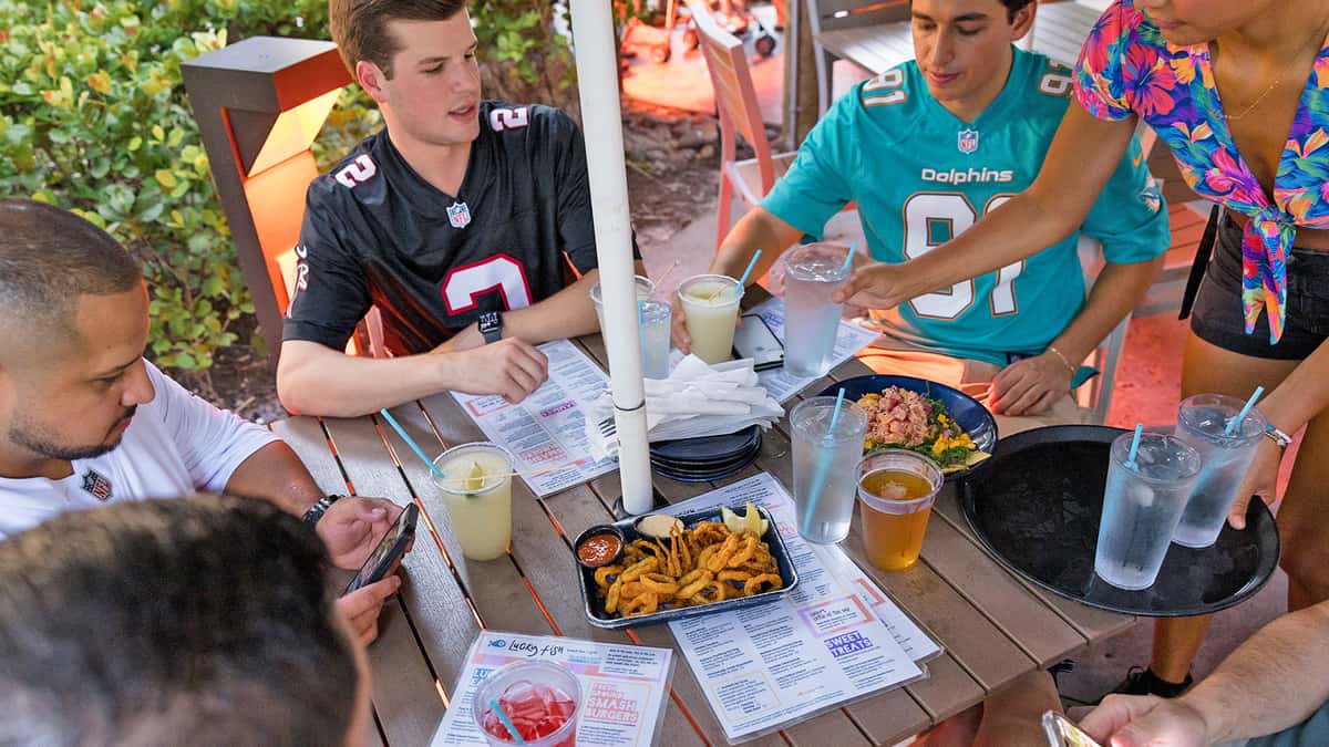 Guests sitting outside at Lucky Fish Beach Bar with beverages and menus
