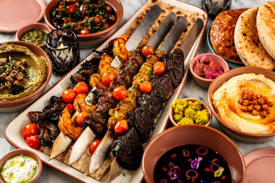 Mediterranean mixed grill platter with grilled kebabs, lamb chops, shrimp, hummus, pita bread, and traditional mezze dishes.