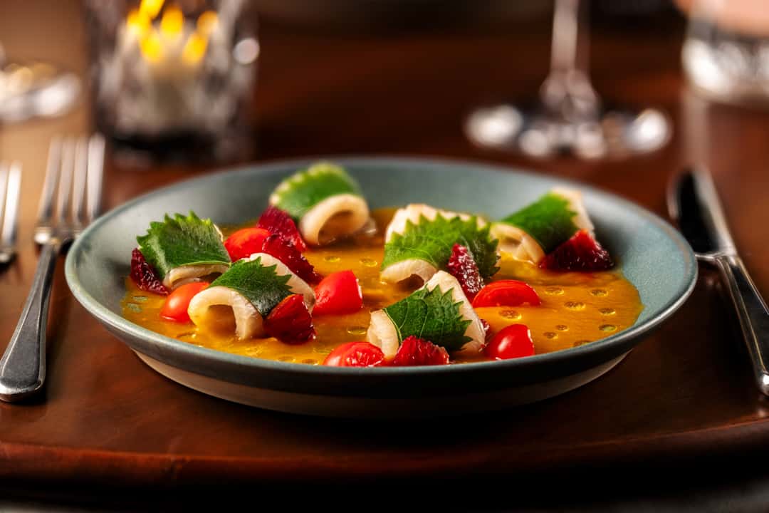 Artfully plated dessert with fresh berries, cream, and colorful garnishes in an upscale restaurant setting.