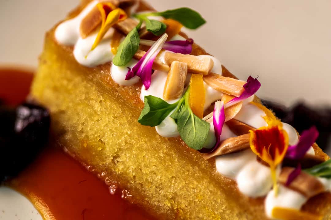 Crispy corn-crusted appetizer topped with creamy dollops, microgreens, pickled vegetables, and edible flowers.