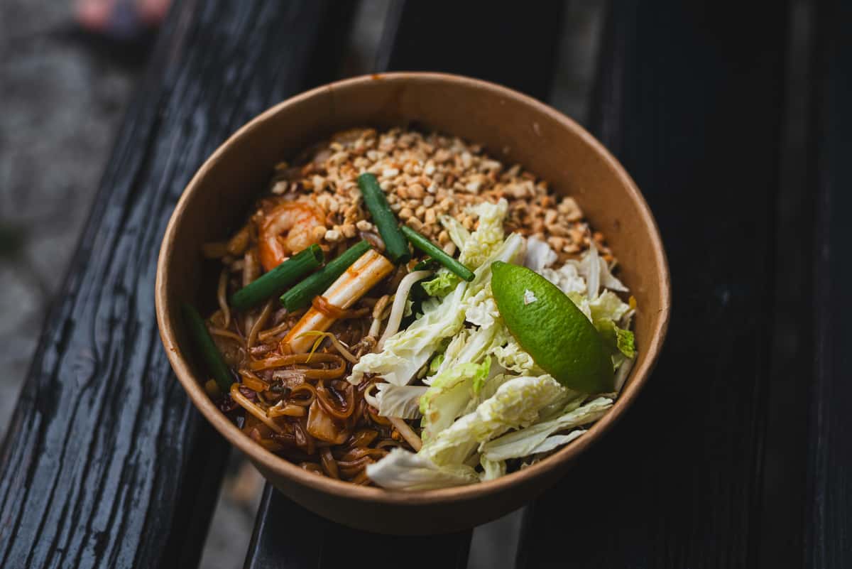 Thai noodle bowl with shrimp, peanuts, cabbage, scallions, and lime