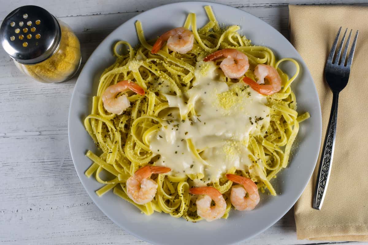 Delicious creamy fettuccine pasta with shrimp, beautifully plated on a rustic wooden table for a gourmet experience.