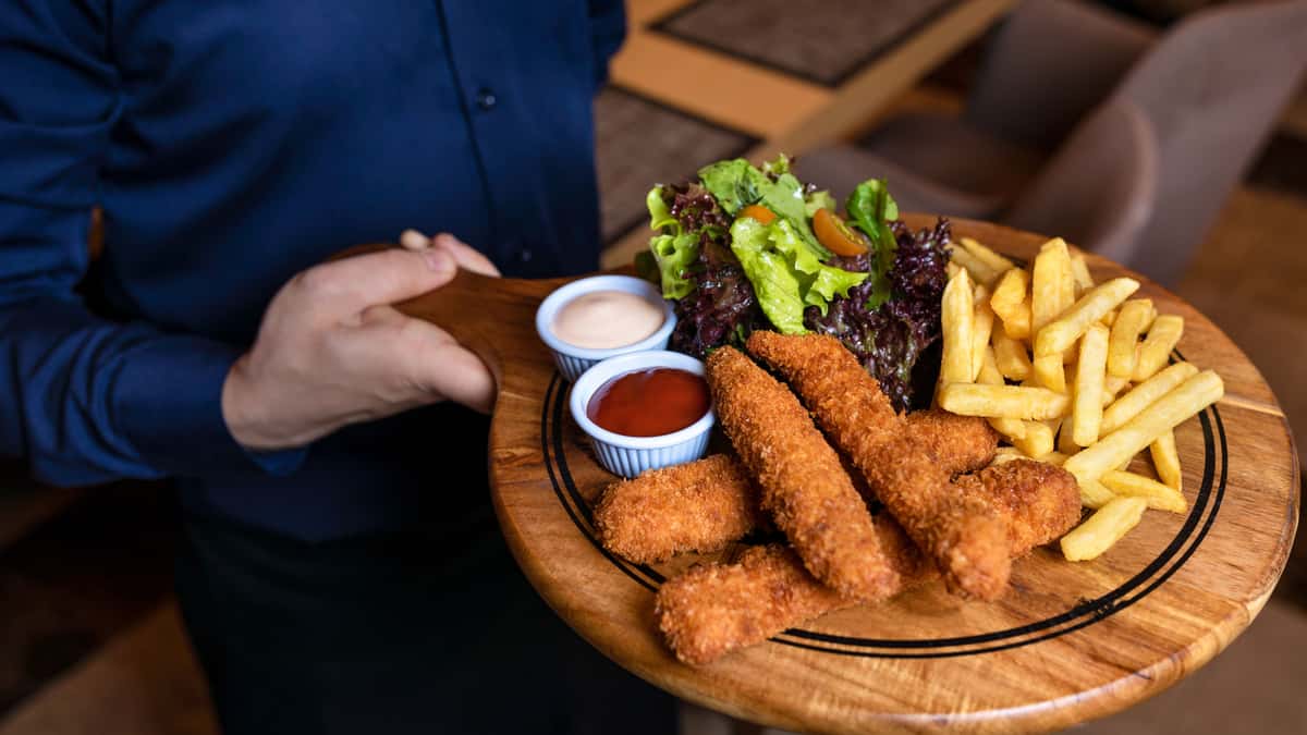 A close-up of a delicious fried fish and fries platter with salad, ketchup, and sauce.