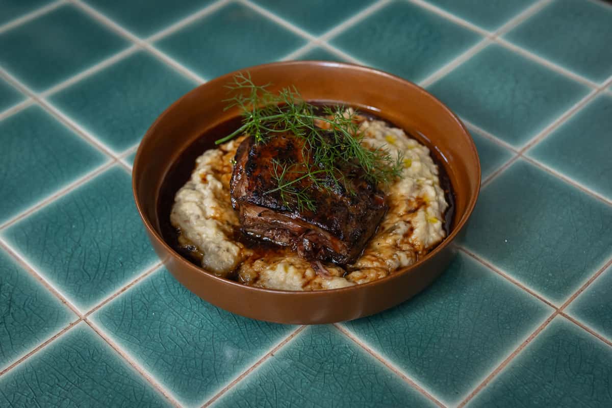 Delicious braised beef served over creamy mashed potatoes with microgreens and radish garnish.
