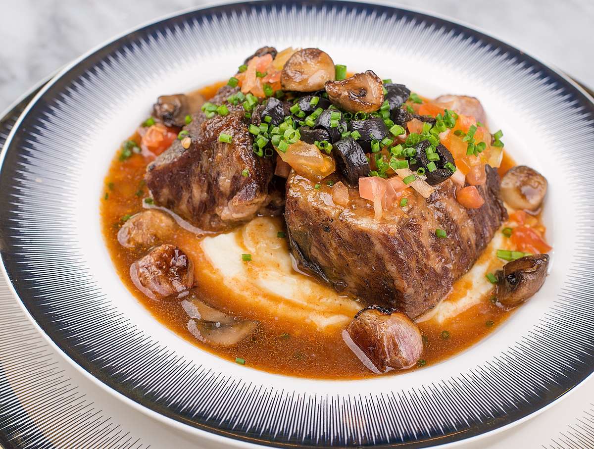 Succulent braised beef short ribs with mushrooms and chives on mashed potatoes.