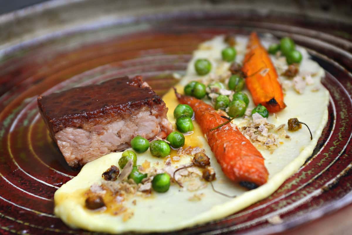 Delicious gourmet dish featuring braised pork, carrots, peas, and mashed potatoes, elegantly plated.