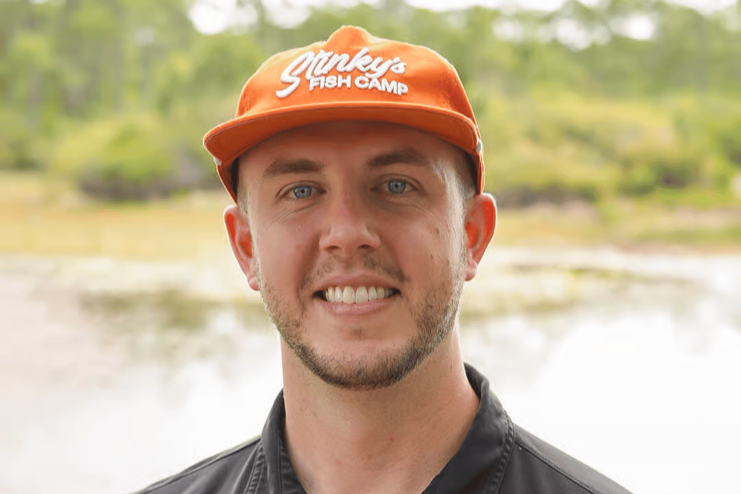 Portrait of a smiling restaurant team member wearing a branded hat and uniform outdoors, showcasing the welcoming staff and hospitality.