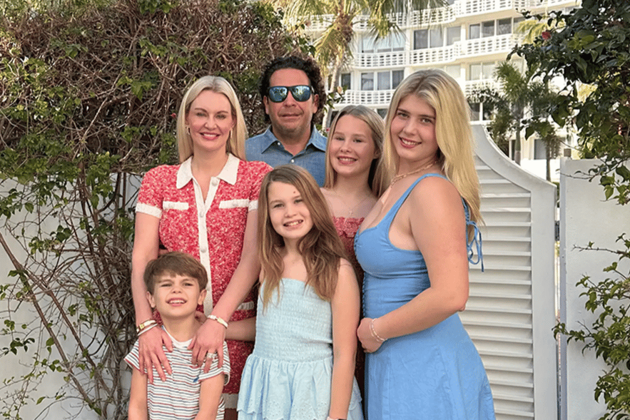 Family portrait outside the restaurant surrounded by tropical landscaping, reflecting the warm, family-owned atmosphere and community spirit.