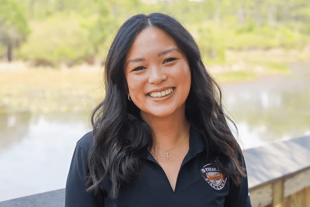 Portrait of a smiling team member wearing a black polo shirt outdoors at the restaurant, creating a friendly and welcoming first impression.