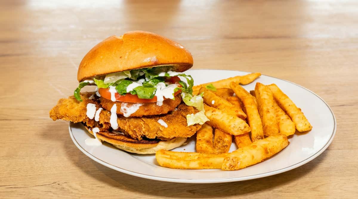 Fried chicken sandwich served with crispy golden fries on a plate