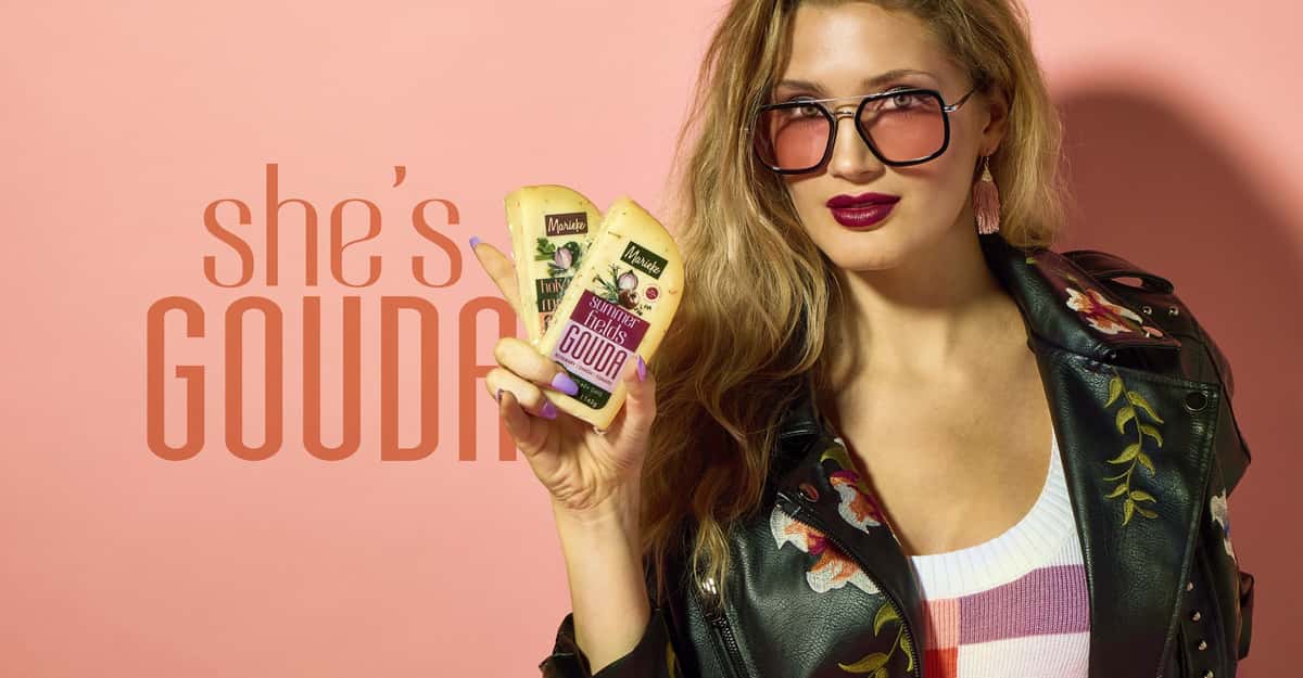 Model holding wedge of Marieke Summer Fields flavored Gouda