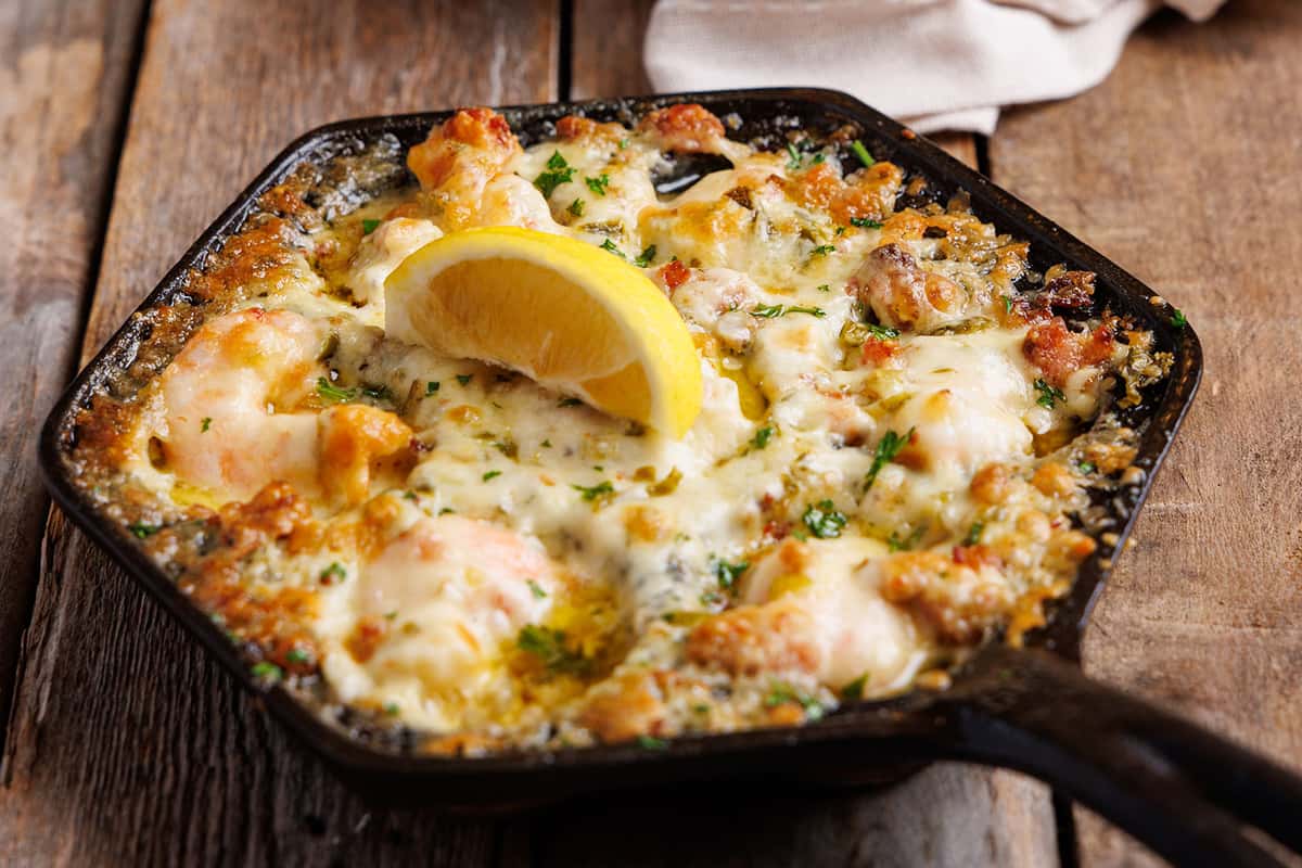 Jacked Up Shrimp served in a skillet featuring broiled shrimp, bacon, jalapeños, & pepper jack cheese