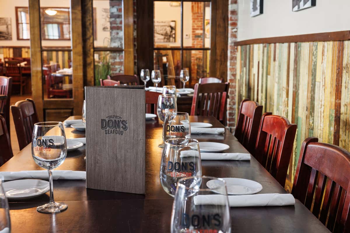Closeup of a dining table setup with glassware, plates, napkins and menus at Don's Seafood