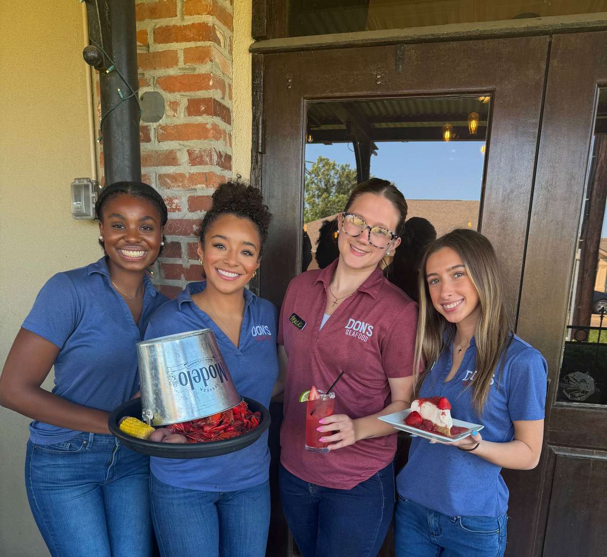 Group photo of four staff members at Don's Seafood holding food and drinks