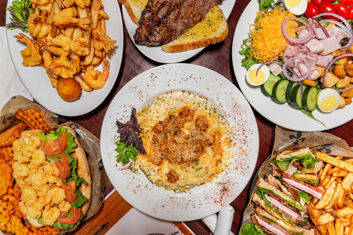 Assorted Southern-style dishes including shrimp pasta, fried shrimp, steak, po'boys, club sandwich with fries, and chef salad.