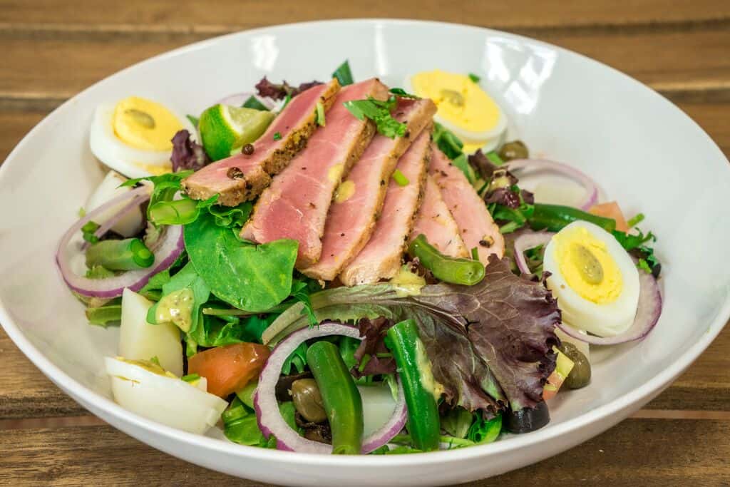 Organic spring mix, seared tuna, boiled egg, green beans, black olives, capers, tomatoes, and potatoes with herb lemon dressing