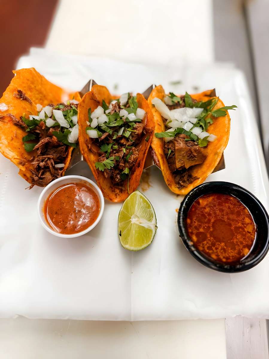Birria tacos served with dipping broth, lime, and salsa.